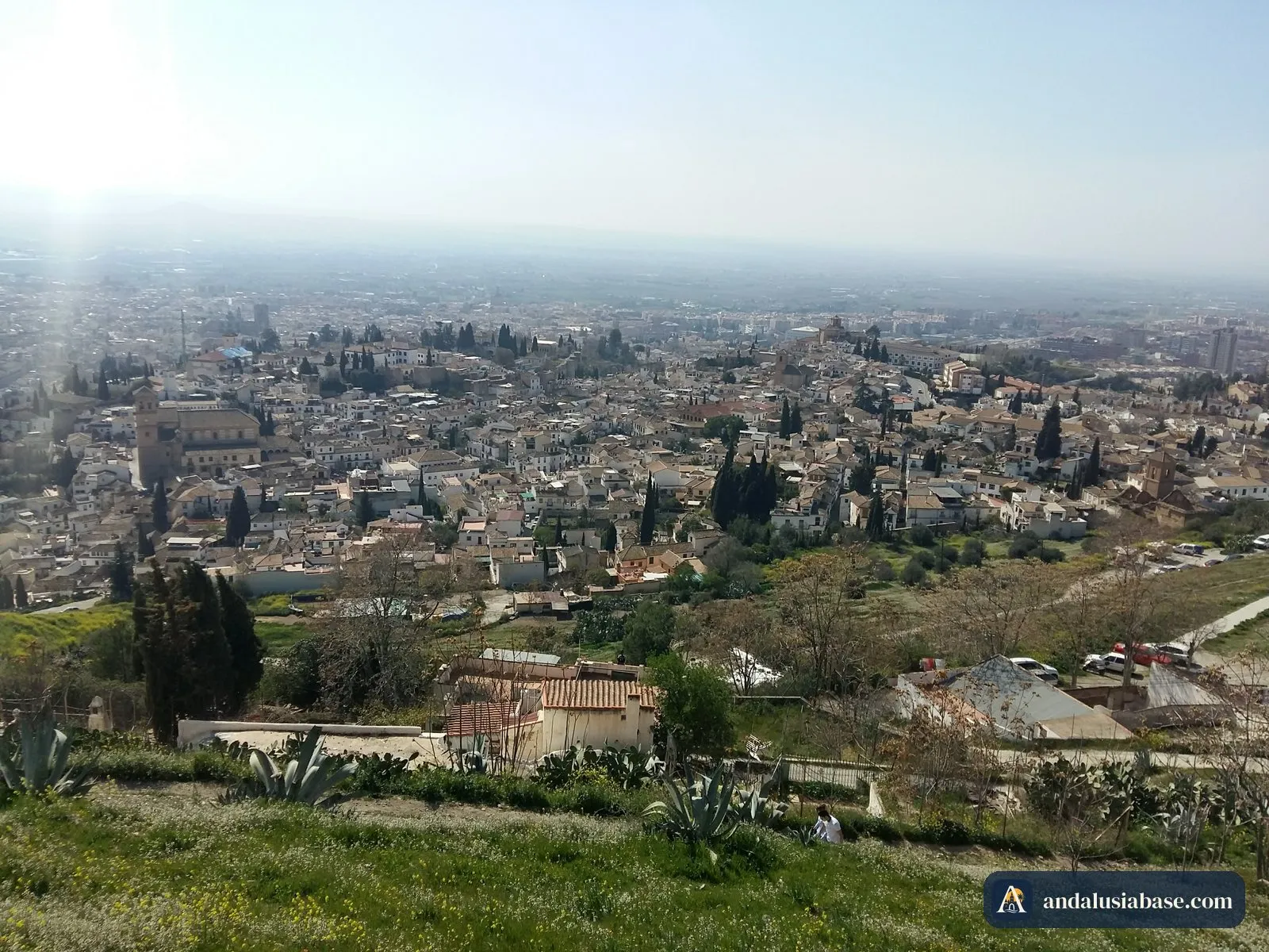 Os telhados e ciprestes do Albaicín aos pés de San Miguel Alto, com a planície de Granada ao fundo