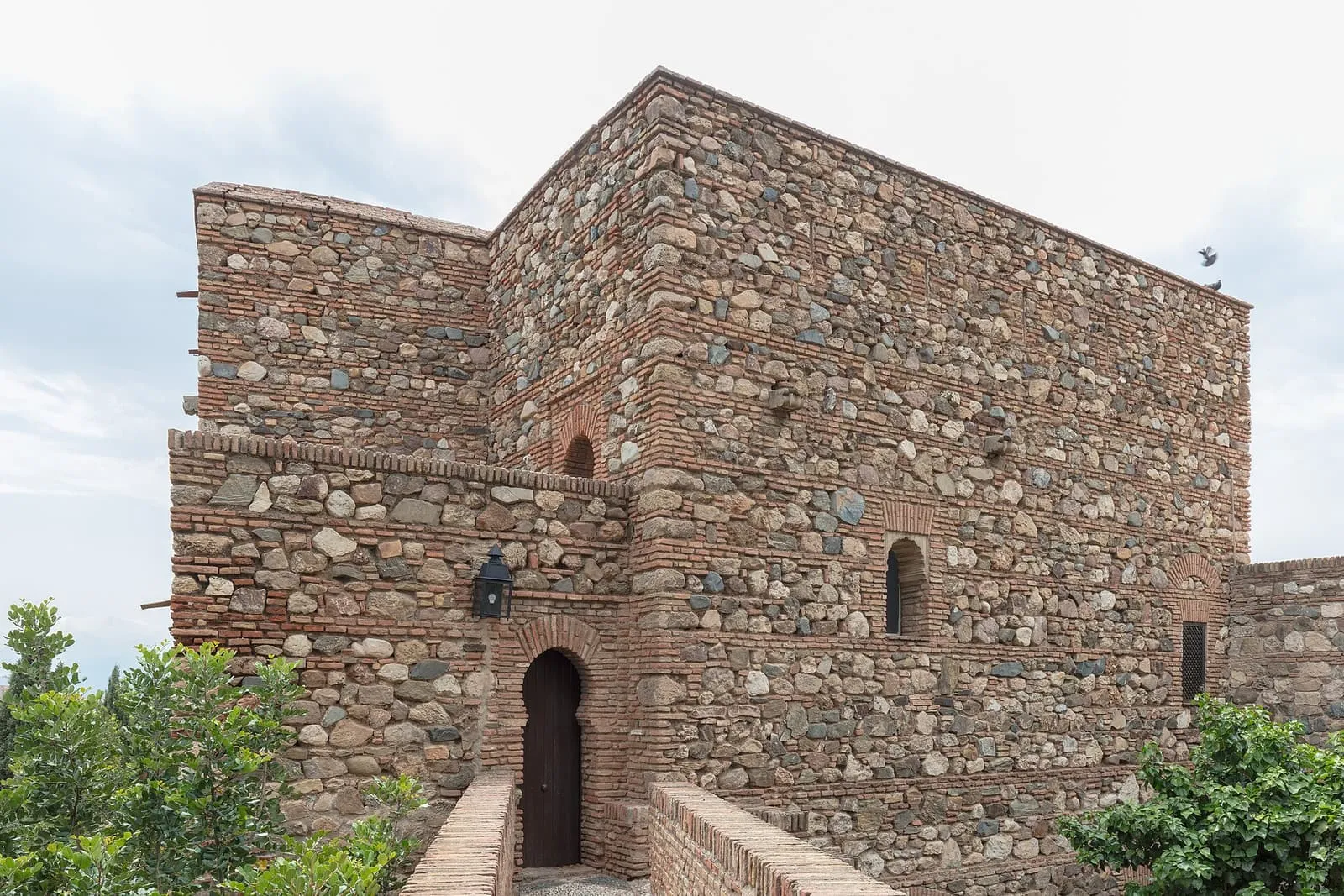 Une tour de pierre et de brique avec une porte cintrée dans l'Alcazaba de Malaga