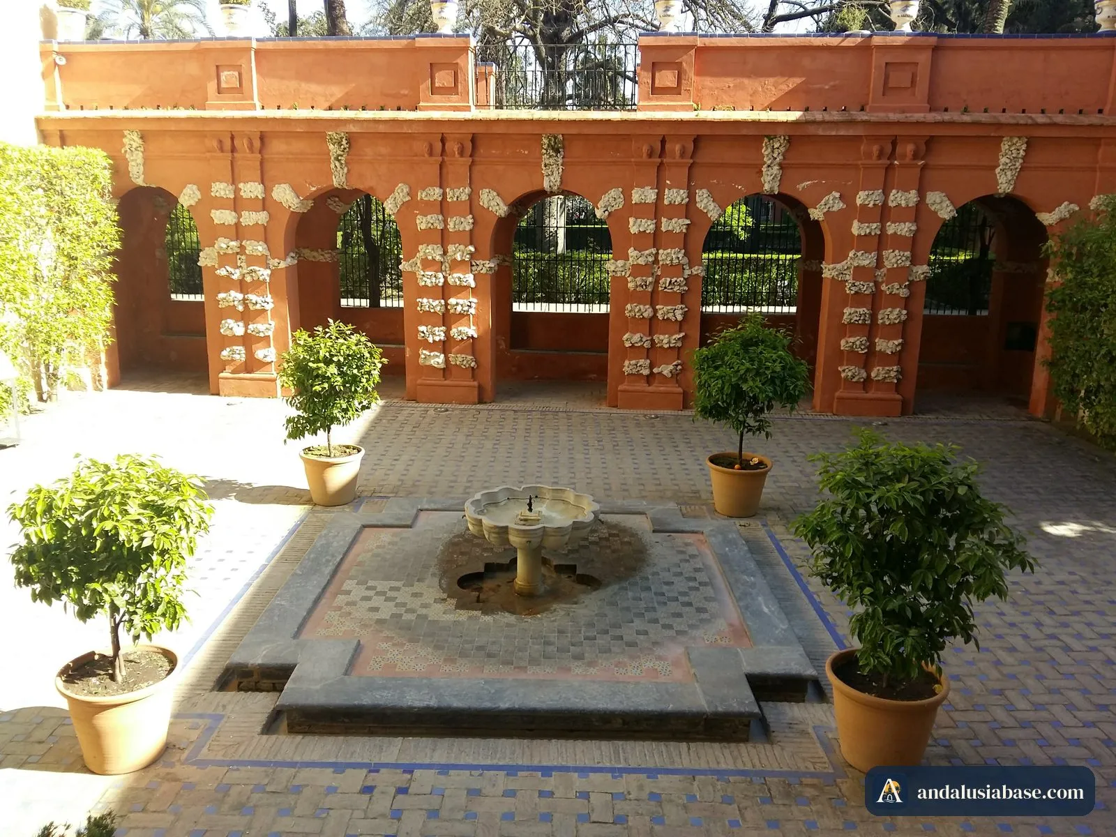 Uma pequena fonte de azulejos com laranjeiras em vaso num pátio ajardinado do Real Alcázar