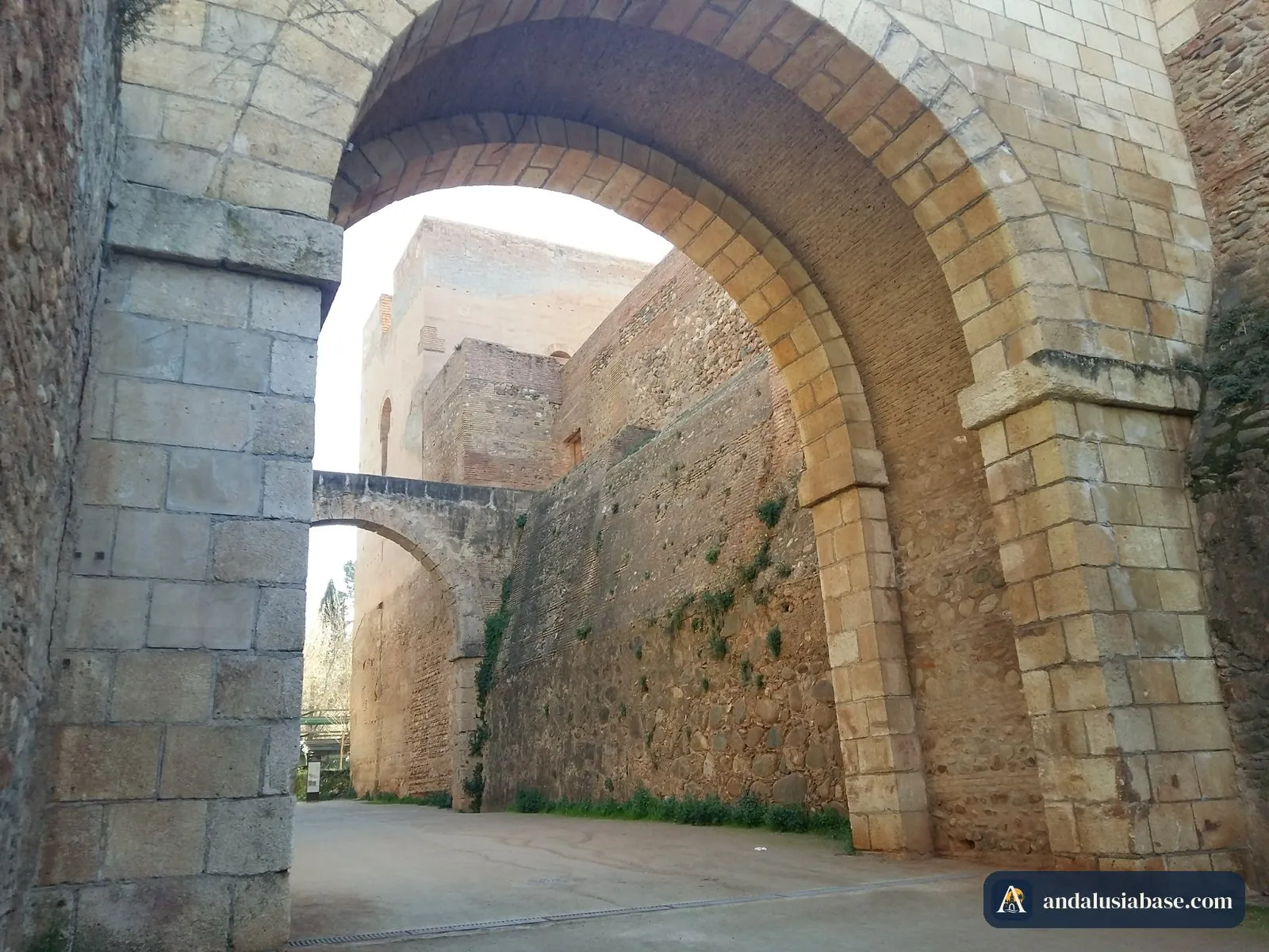 Um enorme arco de pedra sob as muralhas e torres da fortaleza da Alhambra