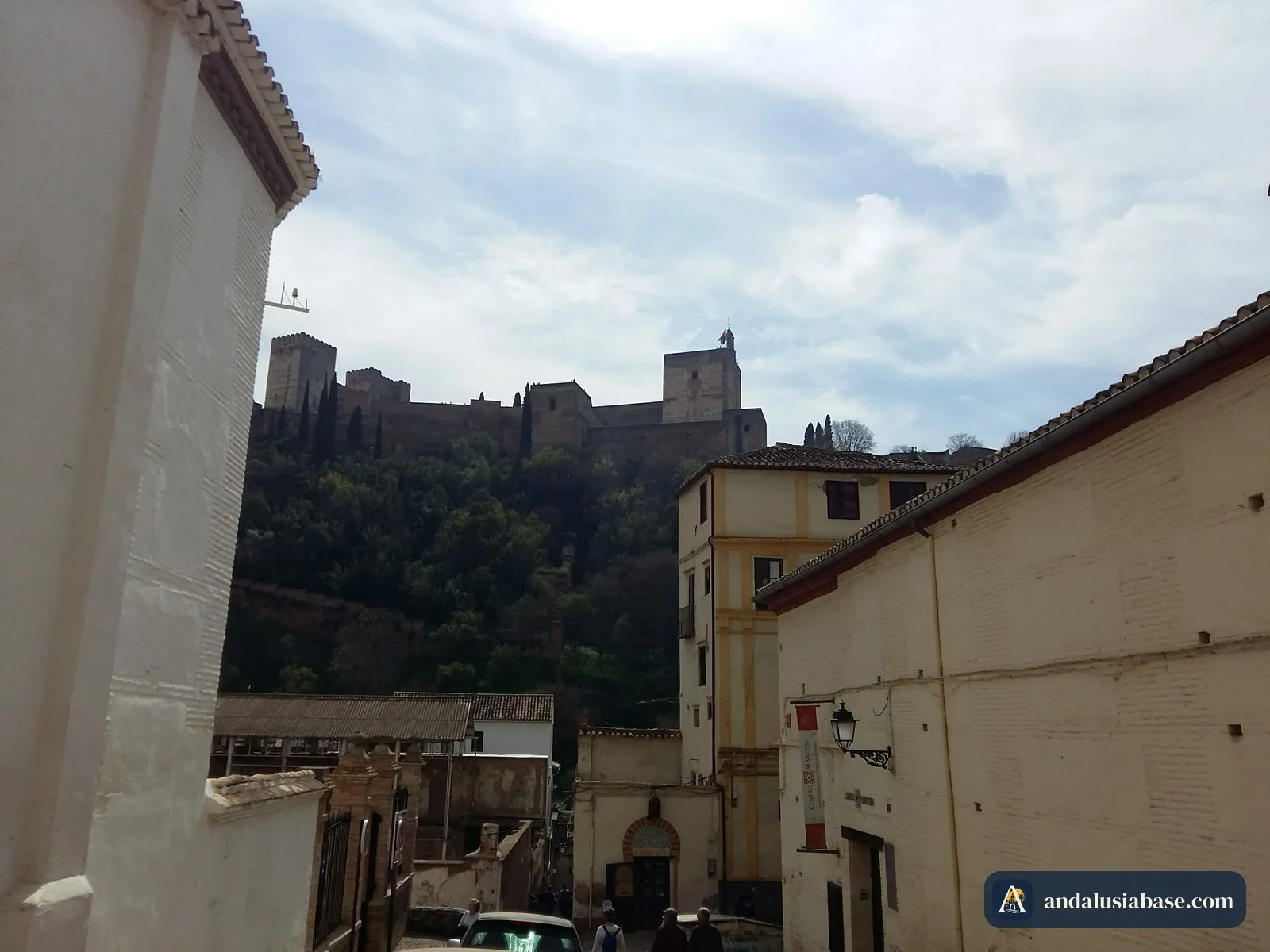 As torres da Alhambra a erguer-se sobre as casas de uma rua de Granada