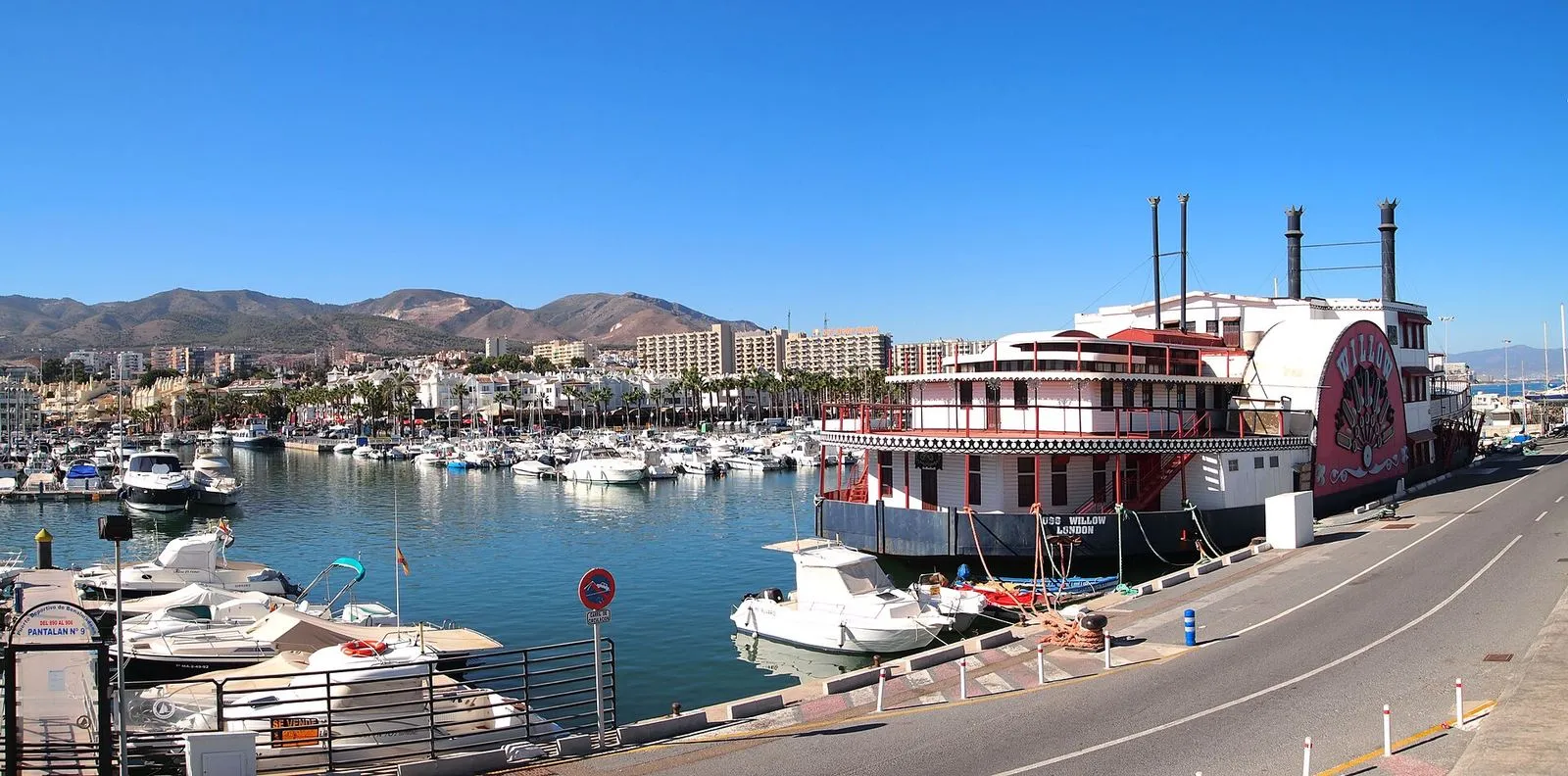 Jachten im Puerto Marina in Benalmádena, mit einem Raddampfer-Restaurant und Bergen im Hintergrund