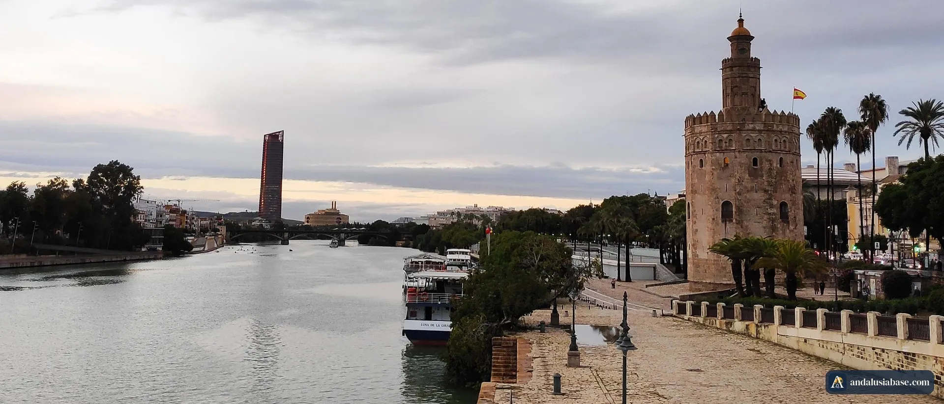 Barcos turísticos atracados no Guadalquivir junto à Torre del Oro, em Sevilha, num fim de tarde nublado