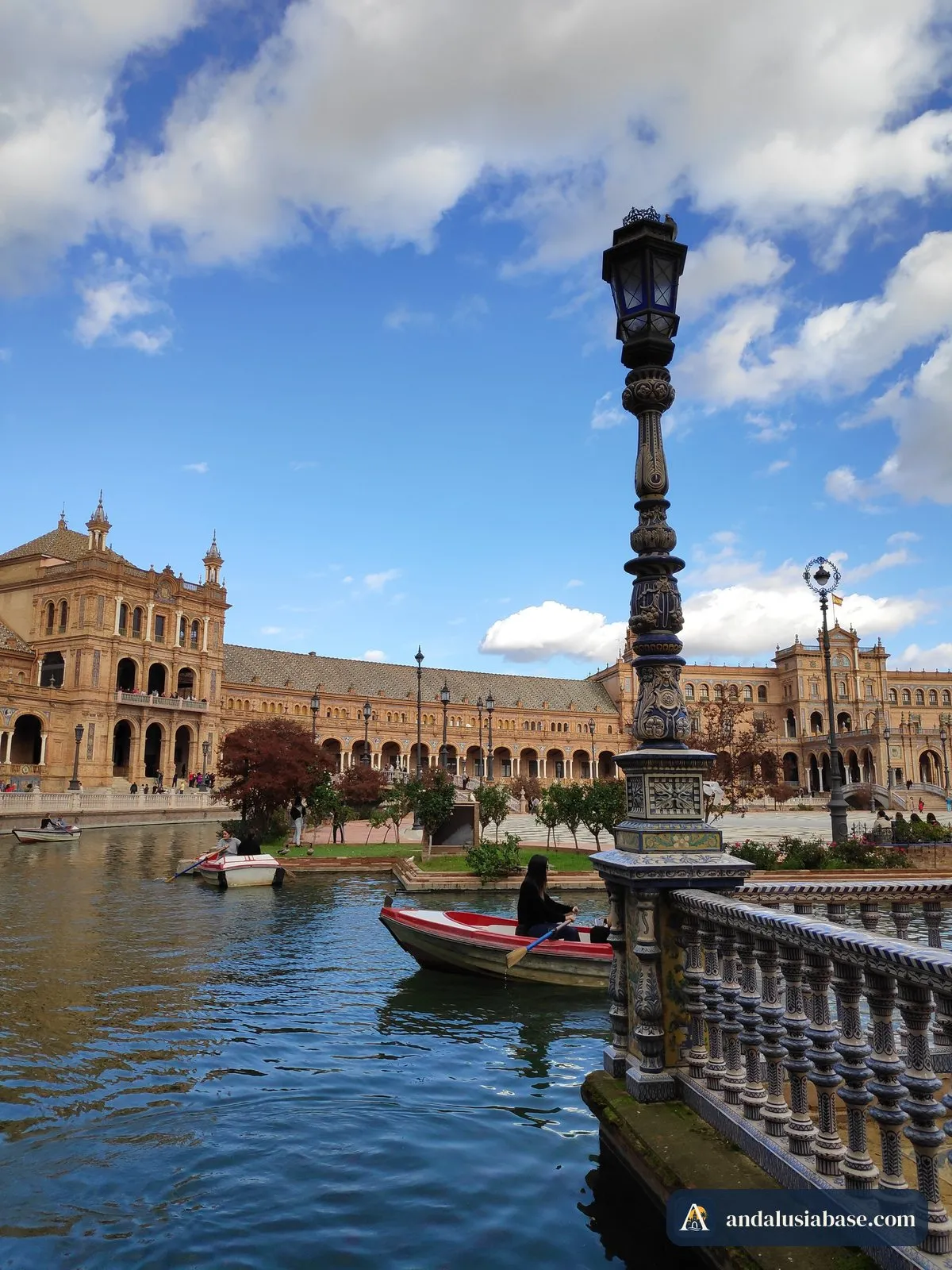 Um barco a remos no canal da Plaza de España junto a um alto candeeiro ornamentado
