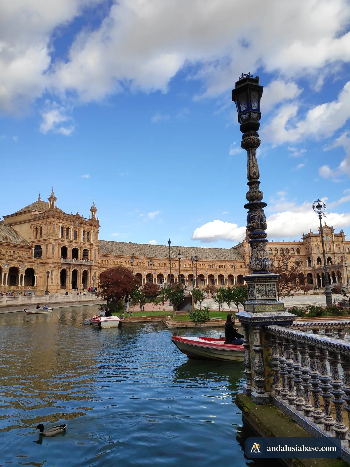 Um barco a remos no canal da Plaza de España, junto a uma balaustrada de cerâmica e um candeeiro