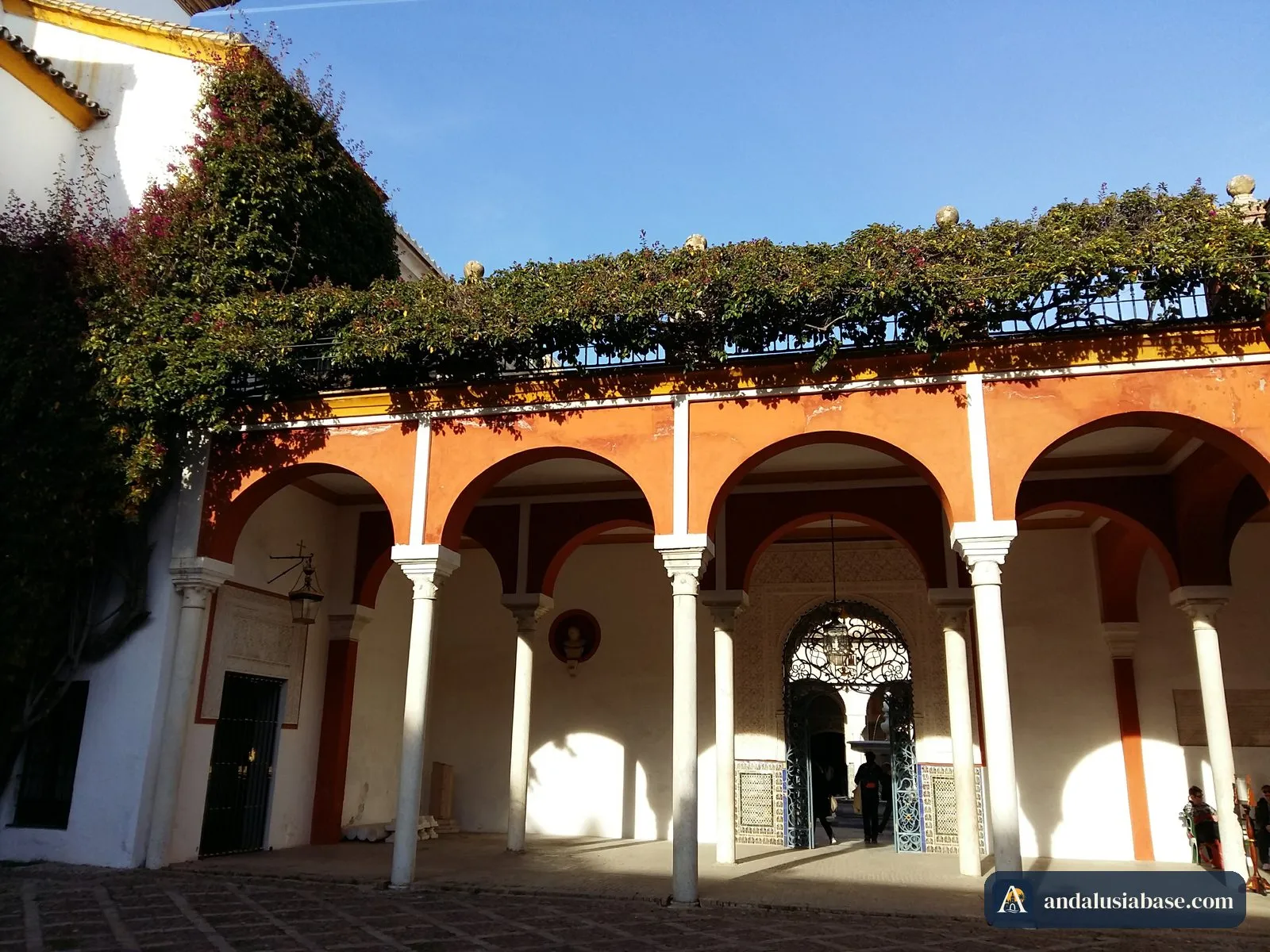 Loggia de arcos com paredes cor de laranja e trepadeiras no jardim da Casa de Pilatos