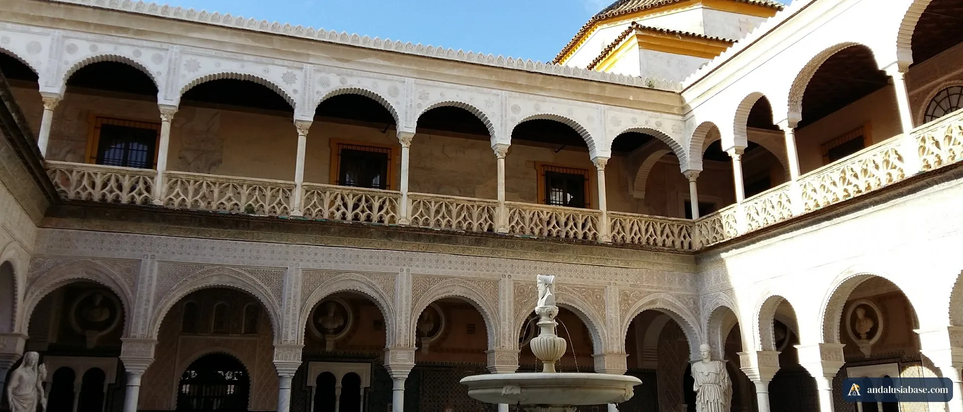 O pátio principal da Casa de Pilatos, com as arcadas mudéjares brancas, a galeria superior, a fonte e as estátuas clássicas