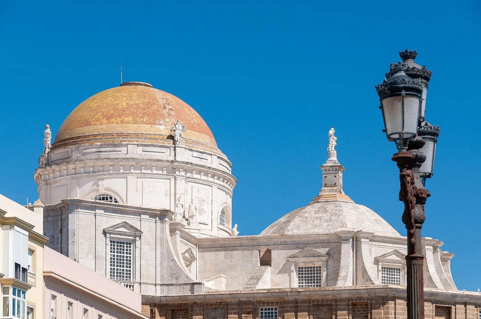 A cúpula de azulejos dourados da Catedral de Cádis contra um céu azul