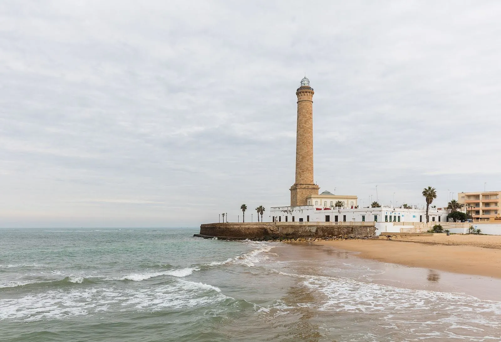 The tall stone lighthouse of Chipiona above the beach and the Atlantic