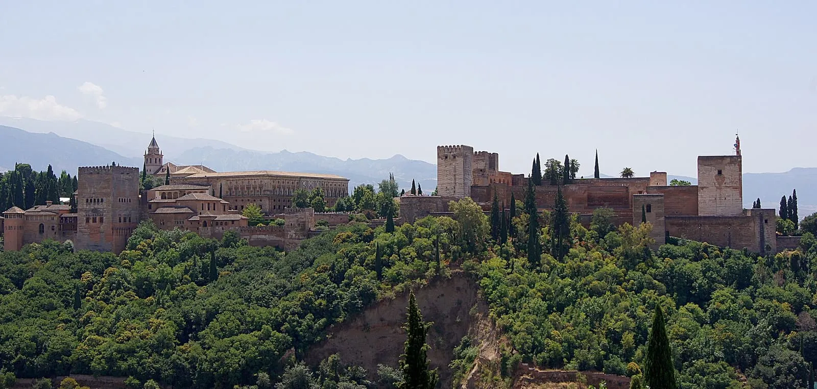 Die Alhambra über bewaldeten Hängen, gesehen vom Mirador de San Nicolás in Granada