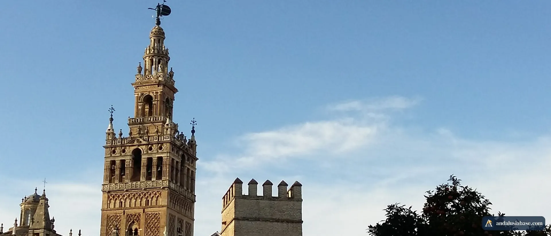 A torre sineira da Giralda ergue-se sobre as muralhas ameadas e as laranjeiras do Real Alcázar de Sevilha