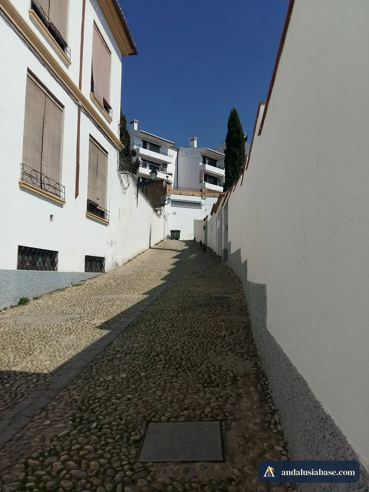 Uma ruela empedrada e tranquila entre muros brancos no alto Albaicín