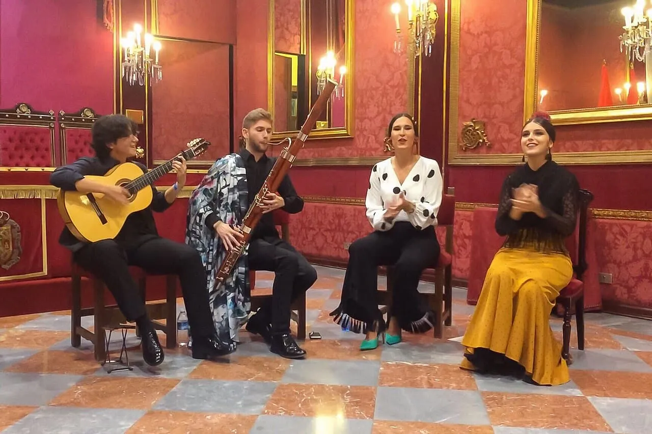 Un groupe de flamenco avec guitare, basson, chanteuse et danseuse dans un salon rouge à Grenade