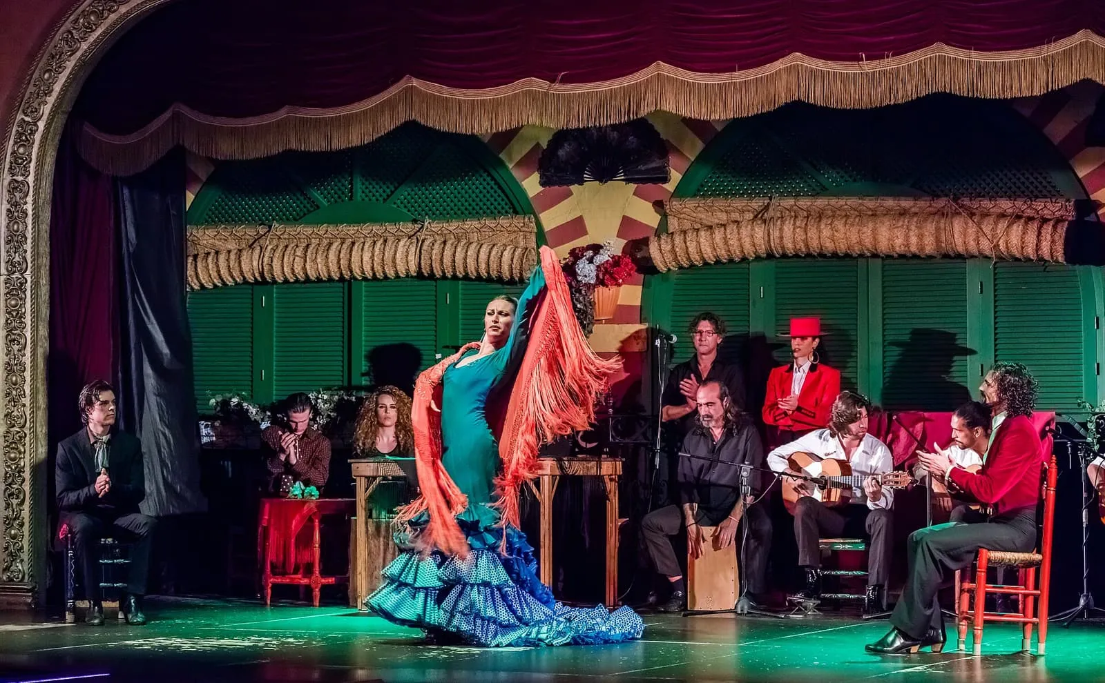 Eine Flamencotänzerin im Rüschenkleid mit Musikern auf der Bühne des Palacio Andaluz in Sevilla