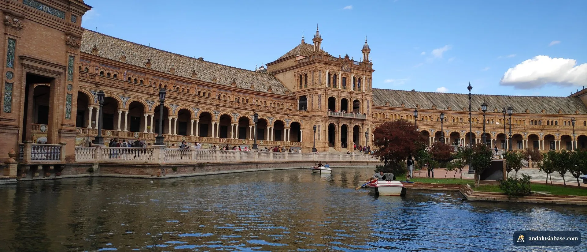 O canal e as arcadas de tijolo da Plaza de España sob um céu azul, em Sevilha