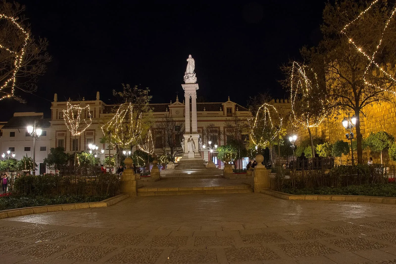 La Plaza del Triunfo de noche, con el monumento a la Inmaculada y árboles iluminados, Sevilla