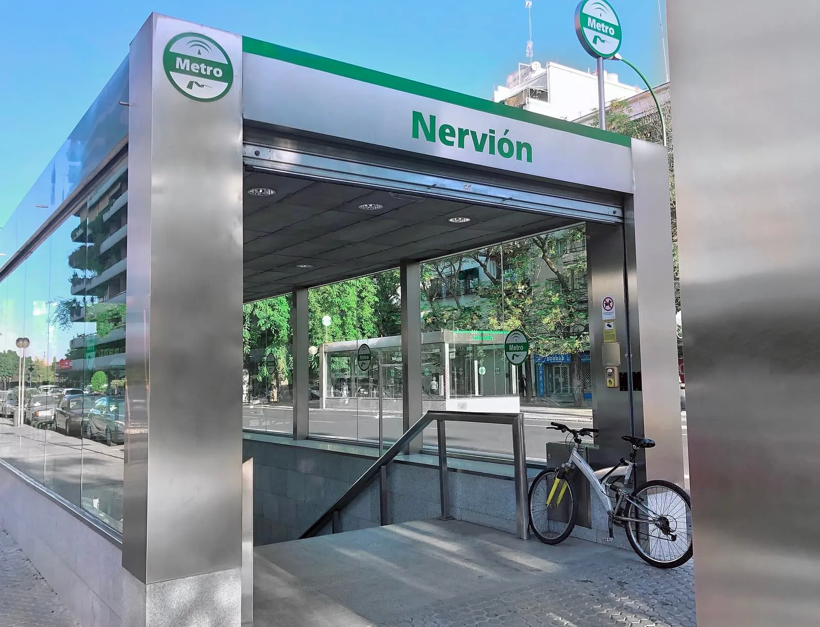 El acceso de cristal y acero a la estación Nervión del Metro de Sevilla, con una bicicleta aparcada