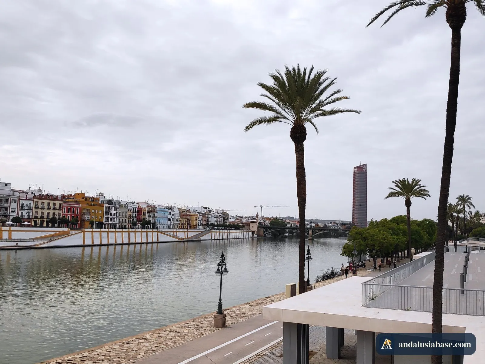 As casas coloridas da Calle Betis na margem de Triana do Guadalquivir, com palmeiras em primeiro plano