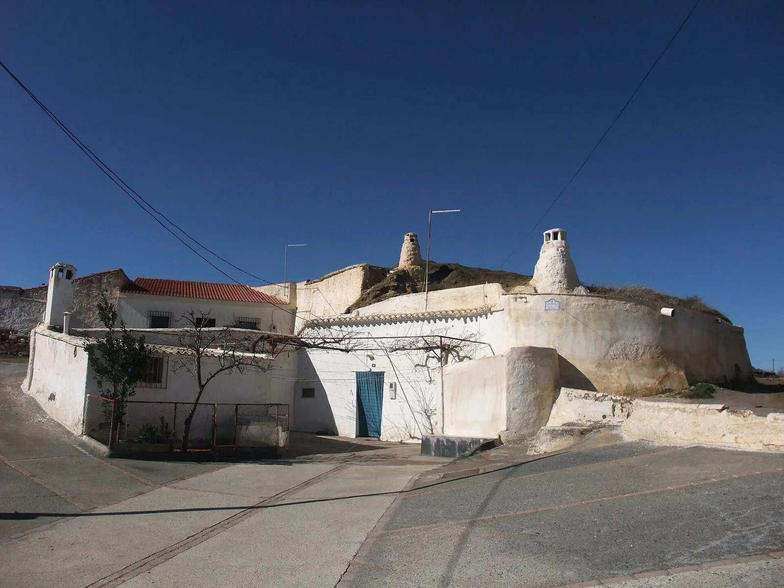 A whitewashed cave house with its round chimneys in the cave quarter of Guadix