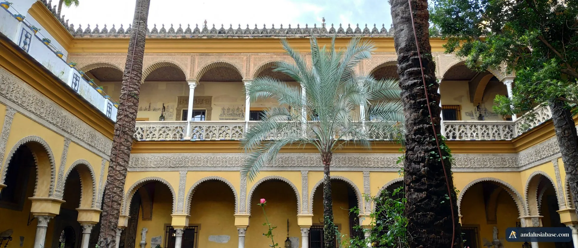 O pátio principal com arcadas do Palacio de las Dueñas, em Sevilha, com palmeiras altas e jardim