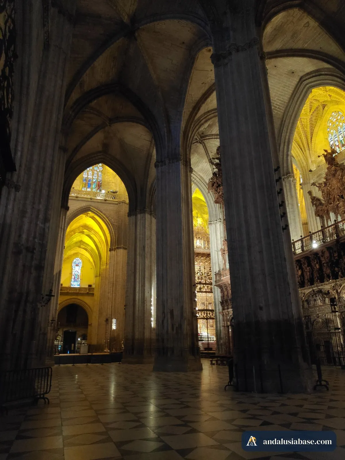 Enormes pilares fasciculados e arcos ogivais ao longo das naves da Catedral de Sevilha