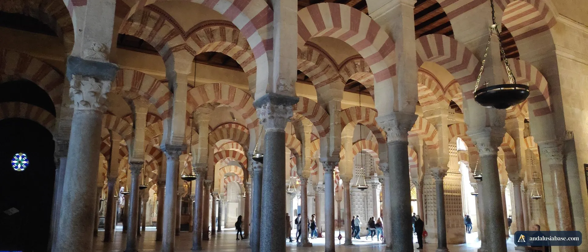 Filas de arcos de ferradura vermelhos e brancos sobre colunas de mármore na sala de oração da Mesquita de Córdoba