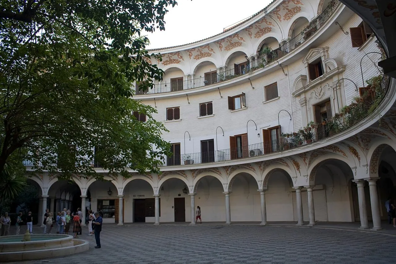 La fachada curva con soportales de la Plaza del Cabildo de Sevilla, con su fuente
