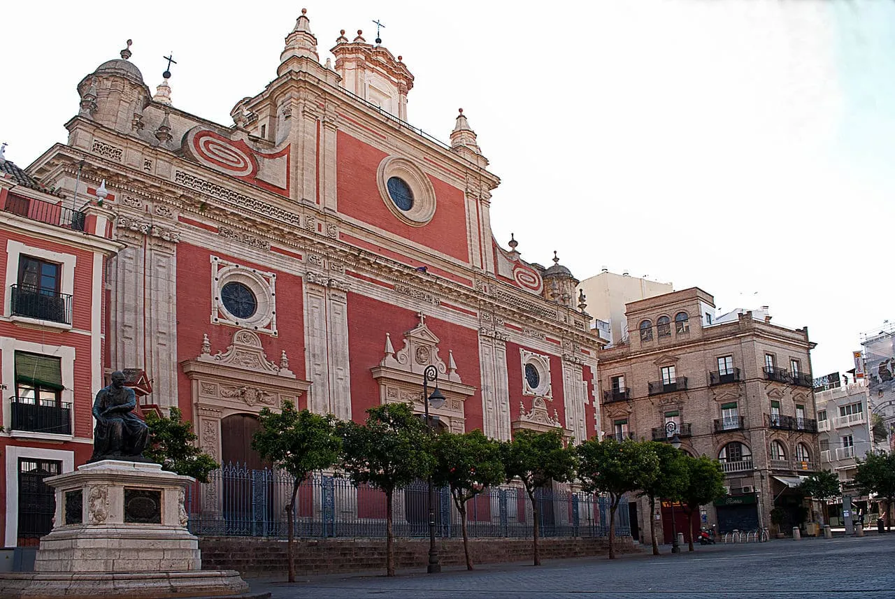 La façade rouge et blanche de l'église du Salvador sur sa place à Séville
