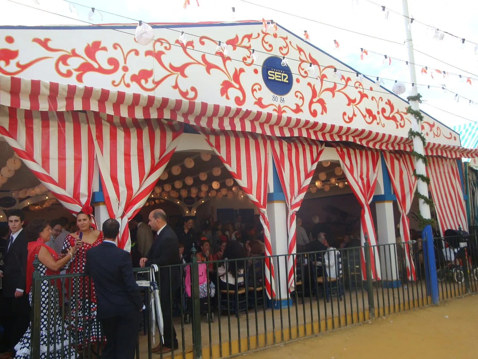 Persone davanti a una caseta a strisce bianche e rosse alla Feria de Abril di Siviglia