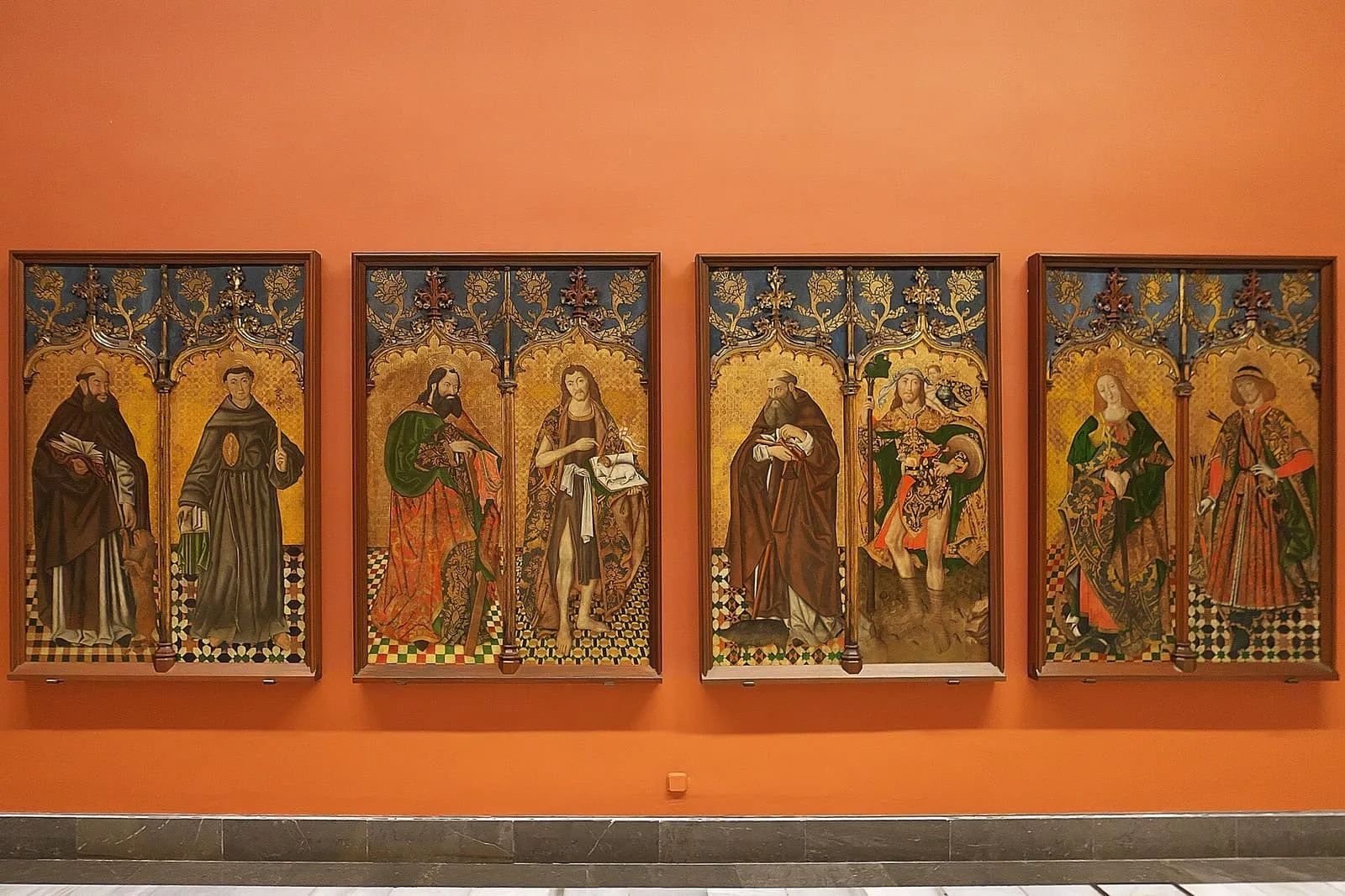 Tavole dipinte di santi del tardo Quattrocento su una parete arancione del Museo de Bellas Artes, Siviglia