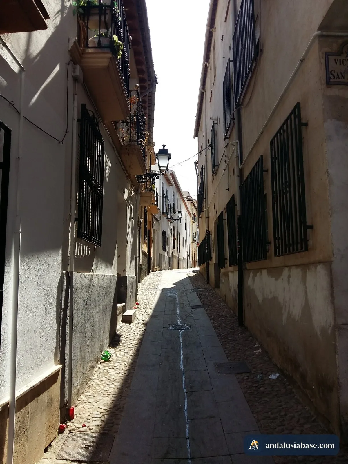 Uma ruela estreita e calcetada com varandas de ferro forjado no centro histórico de Granada