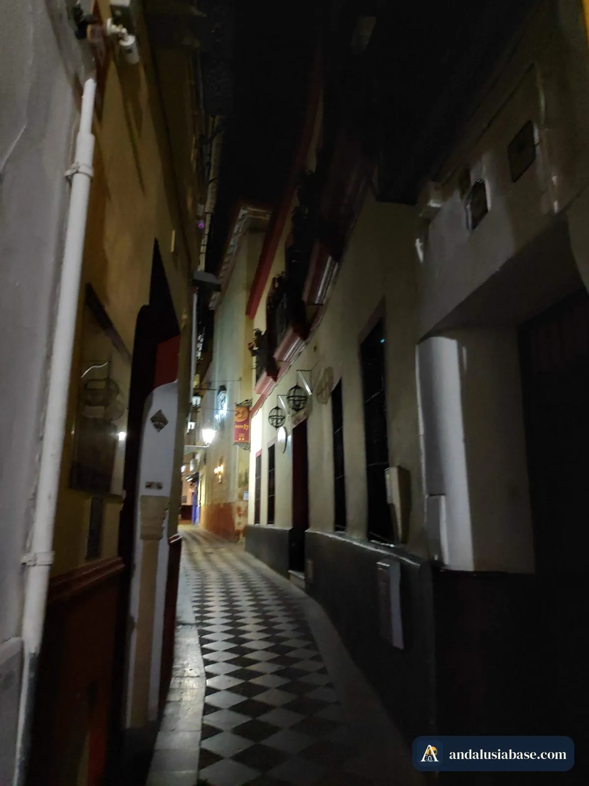 Beco iluminado por lanternas com chão em xadrez em Santa Cruz à noite