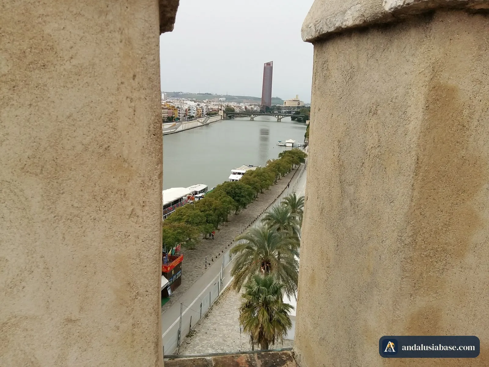 Os barcos turísticos atracados no cais junto à torre, vistos entre as ameias