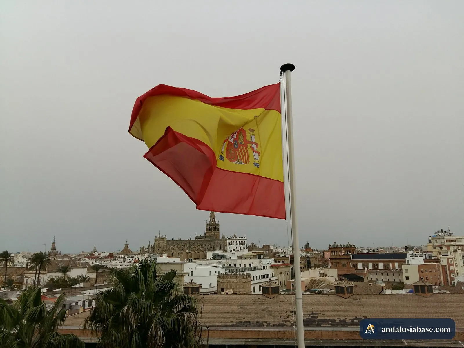 A bandeira de Espanha no terraço da Torre del Oro, com a Giralda e a catedral no horizonte
