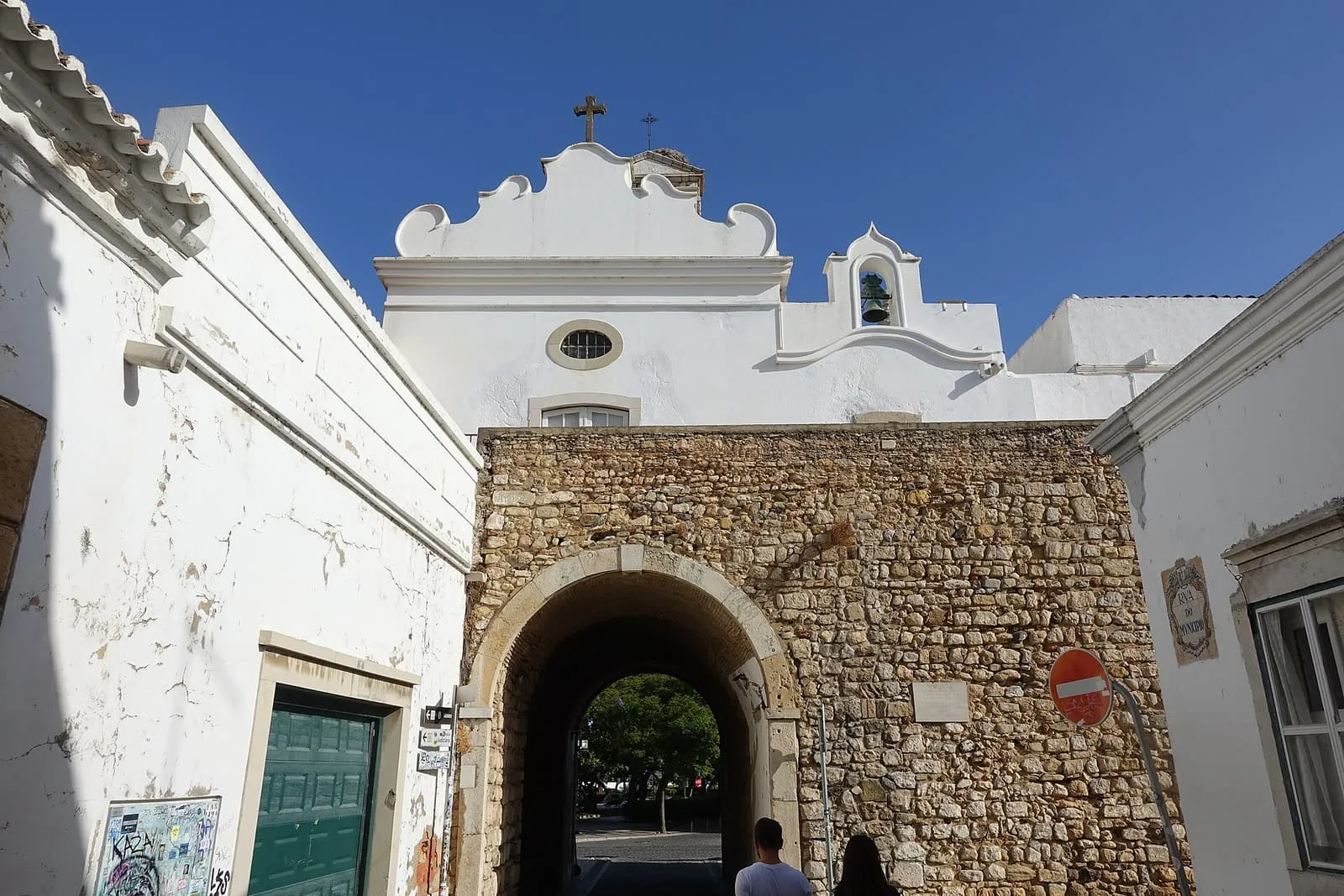La puerta de piedra del Arco da Vila, entrada al casco antiguo de Faro, bajo una espadaña encalada