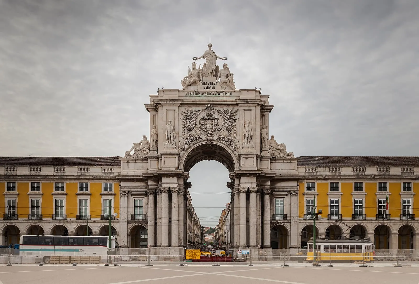 Der Arco da Rua Augusta an der Praça do Comércio in Lissabon mit gelben Arkadenbauten und Straßenbahn