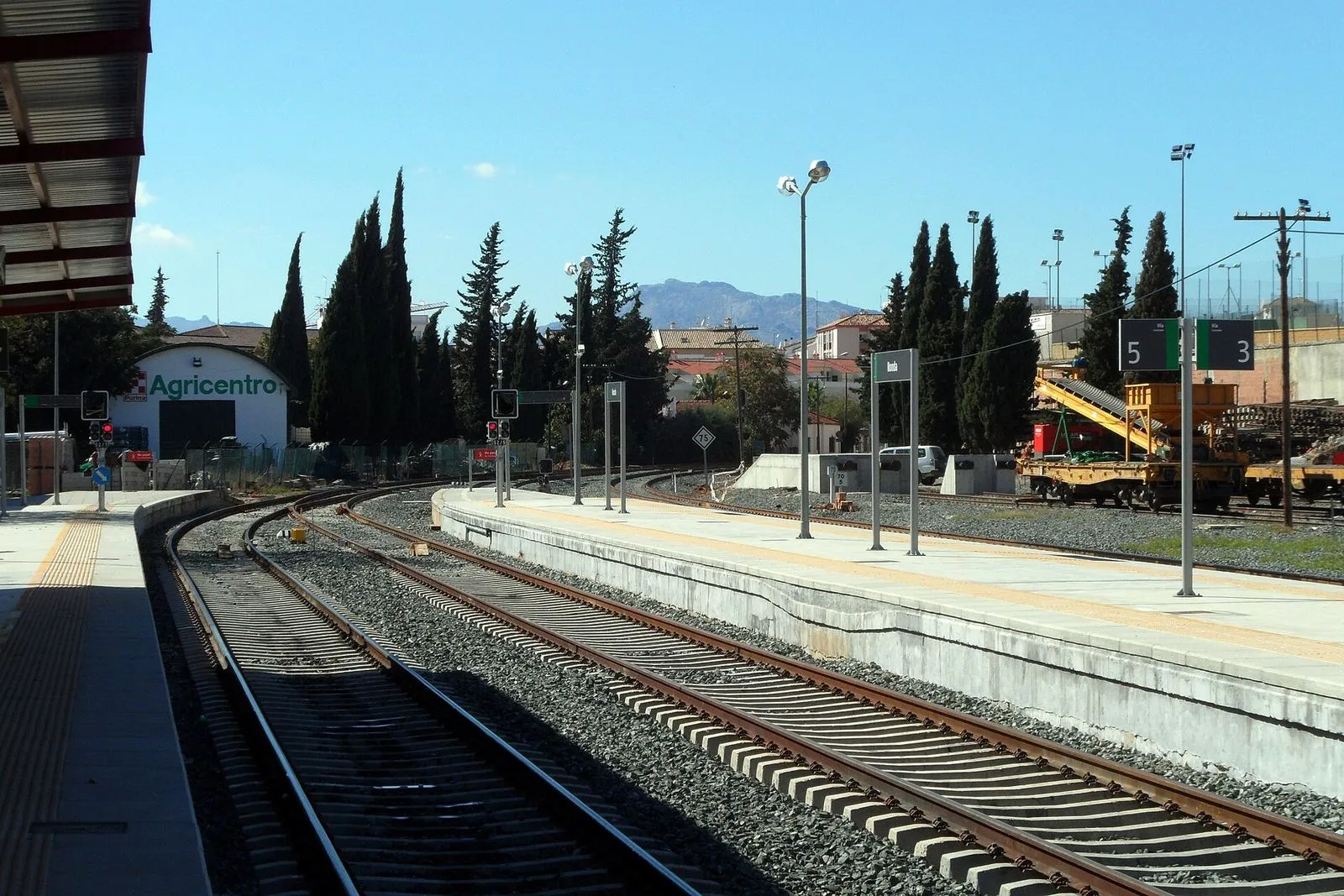 Os cais da estação de comboios de Ronda sob um céu azul, com as montanhas ao fundo