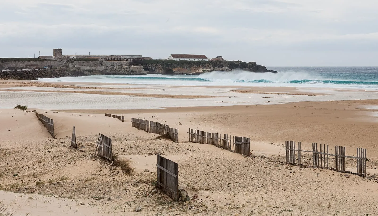 Dunes et clôtures en bois sur une plage de Tarifa, face au fort de l'Isla de las Palomas