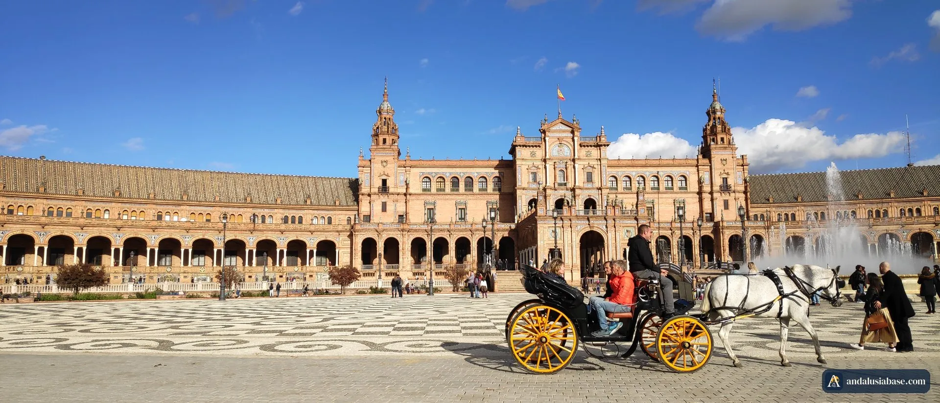Uma charrete de cavalos diante das amplas arcadas da Plaza de España, em Sevilha