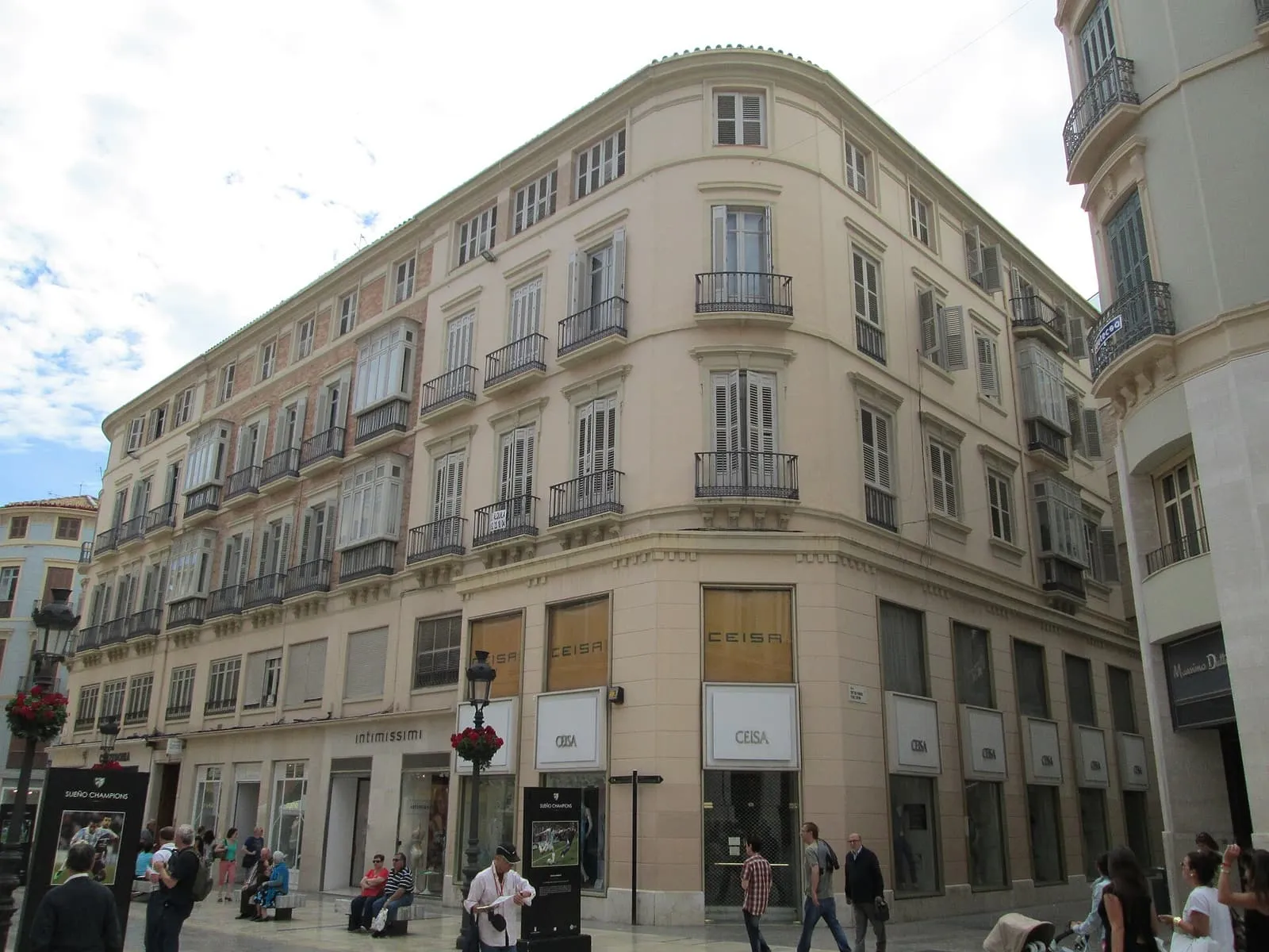 Un palazzo d'angolo color crema con balconi in Calle Larios, la via dello shopping di Malaga