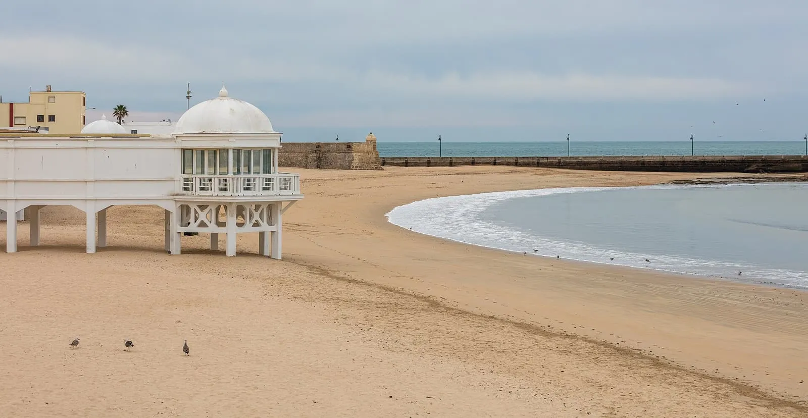 La playa de La Caleta de Cádiz, con el blanco Balneario de la Palma sobre pilotes