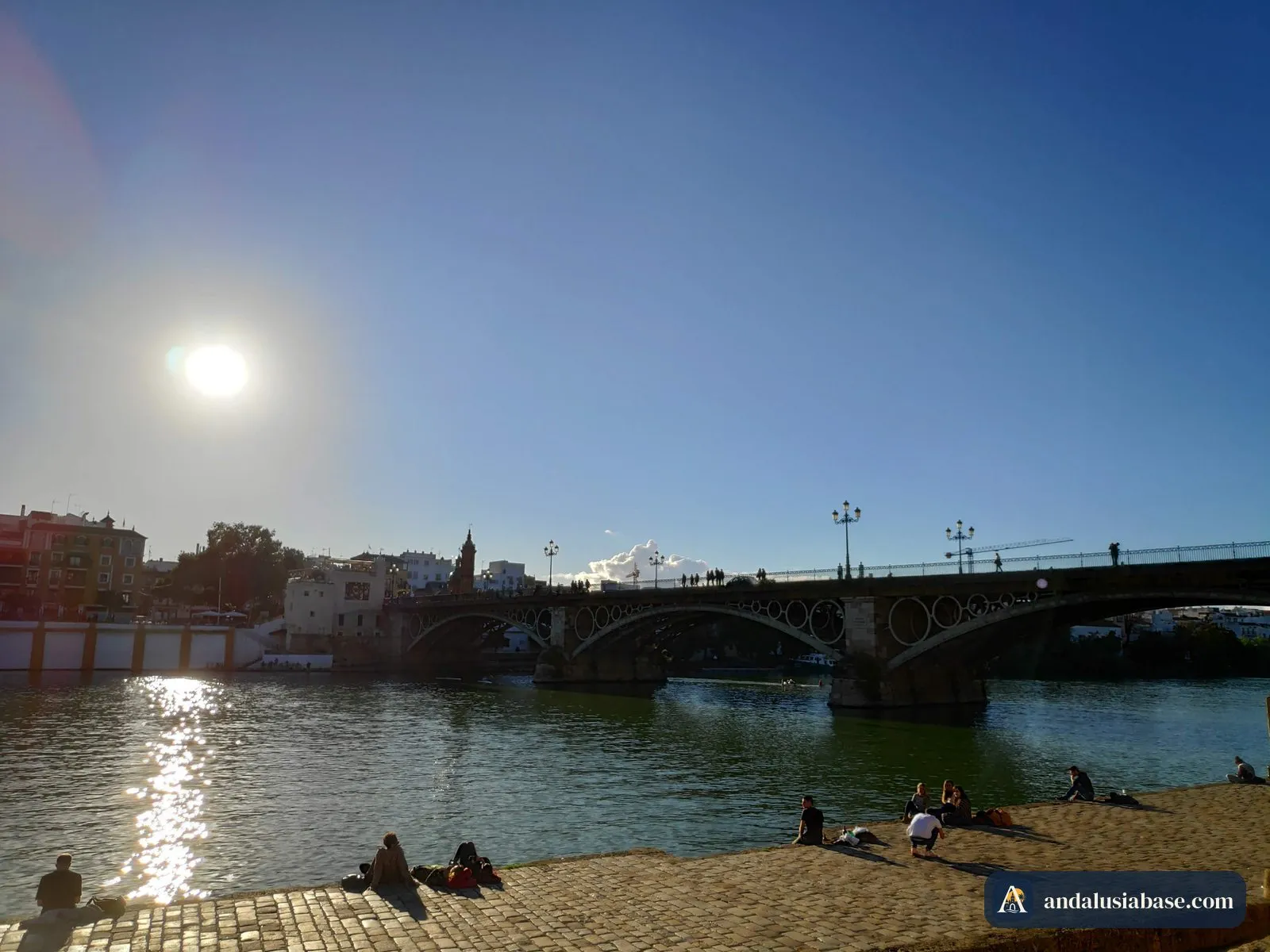 Os arcos de ferro da ponte de Triana em contraluz com o sol baixo de inverno, vistos da margem de Sevilha