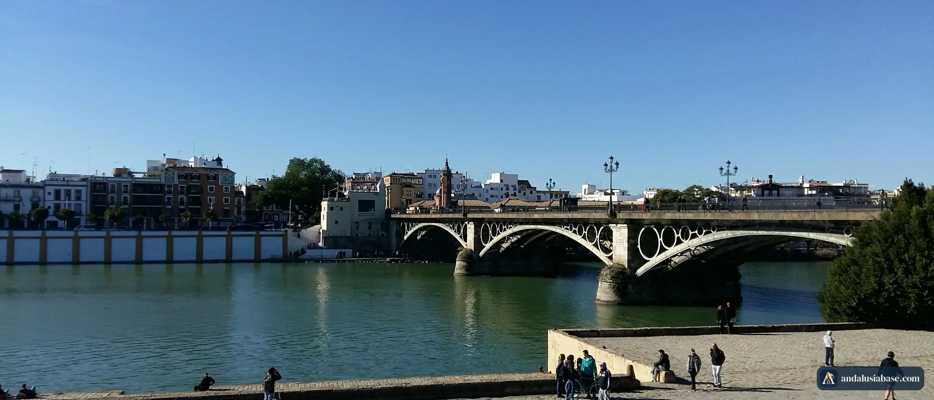 A ponte de Triana (Puente de Isabel II) sobre o Guadalquivir num dia de sol, com a margem de Triana ao fundo