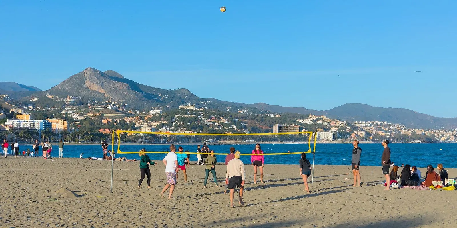 Voleibol de praia num dia de sol na praia de La Malagueta, em Málaga, com as colinas ao fundo