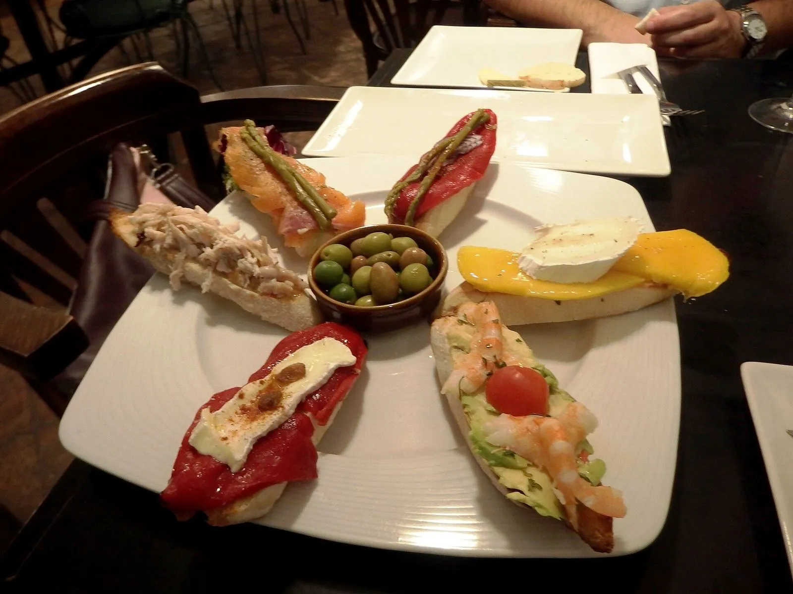 Um prato de tapas em pão torrado com azeitonas num bar de Granada