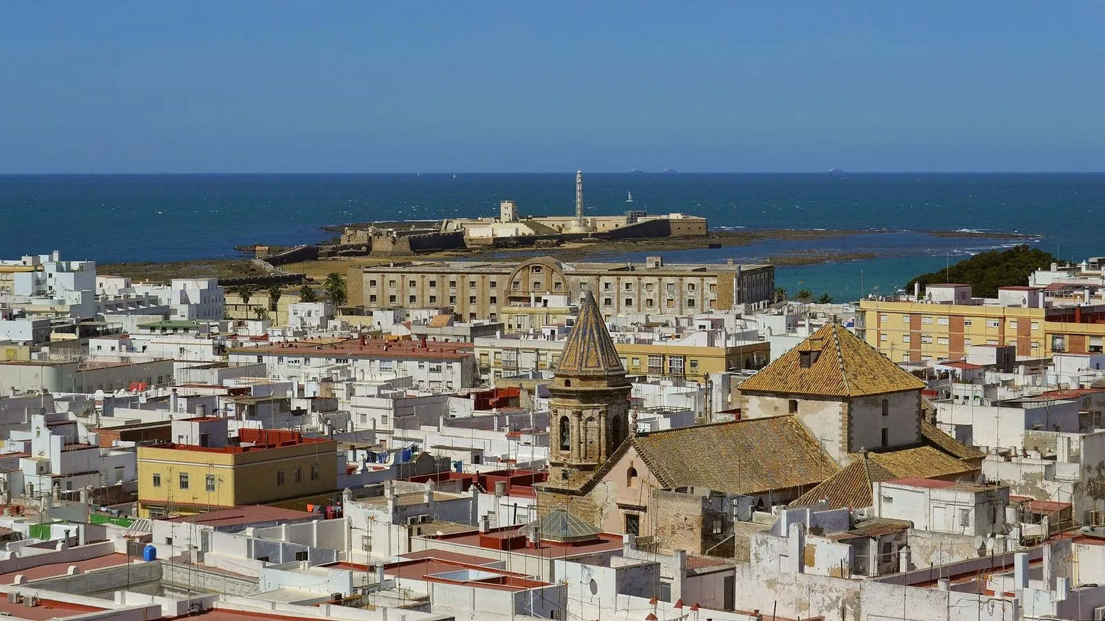 Telhados brancos do centro histórico de Cádis a descer até ao mar e ao Castillo de San Sebastián