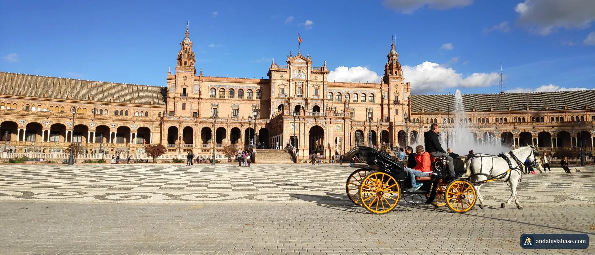 Uma carruagem puxada a cavalo, de rodas amarelas, atravessa a Plaza de España em Sevilha num dia de sol